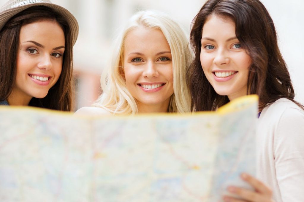 Three woman looking up from a map as they plan their girlfriend getaway.